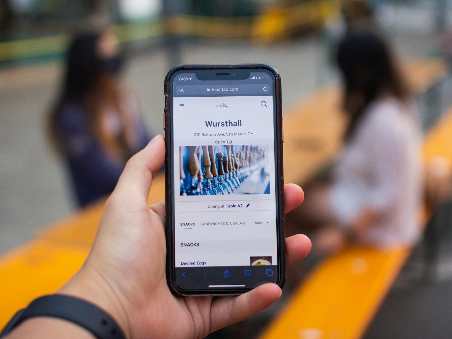 Hand holds smartphone displaying Wursthall restaurant website with menu.