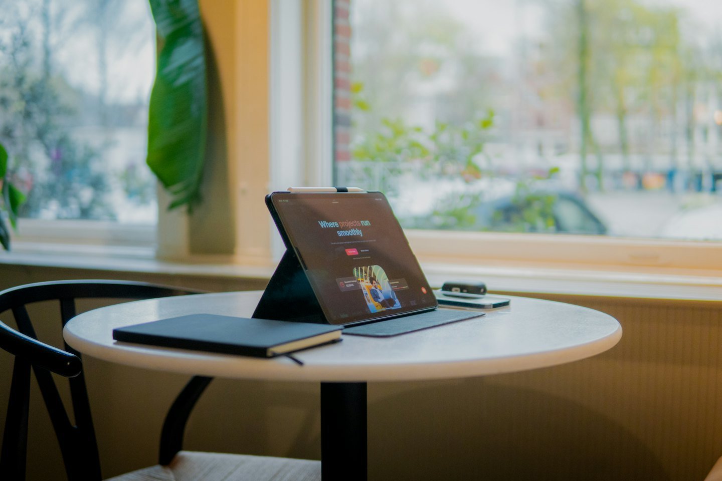 A tablet, notebook, and power bank sit on a white table.